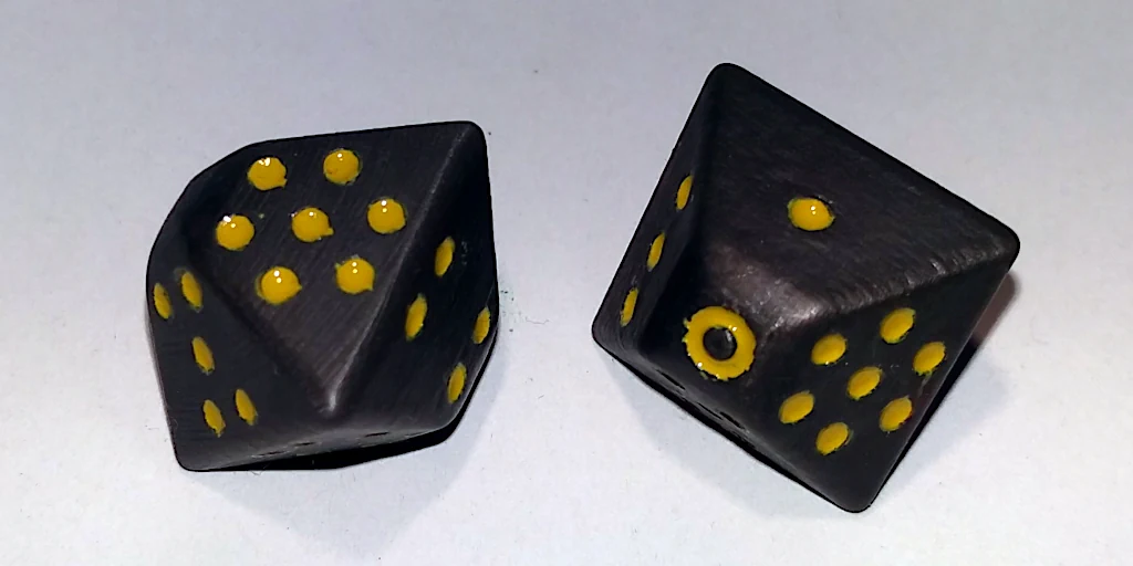 Grey dice painted with yellow dots.